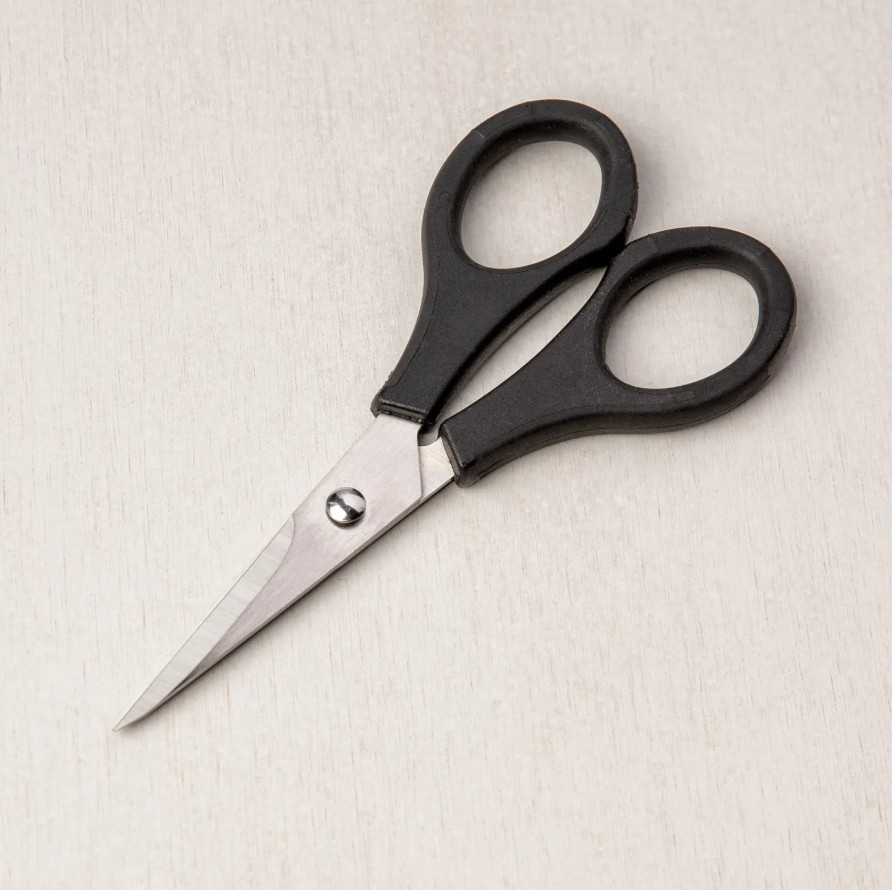 Small pair of precision crafting scissors with sharp stainless steel blades and black handles, placed on a light wooden surface.