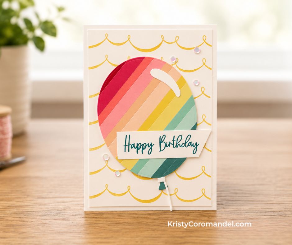 Cream birthday card featuring a large rainbow-striped balloon made from cardstock strips, gold festoon banner background, "Happy Birthday" sentiment