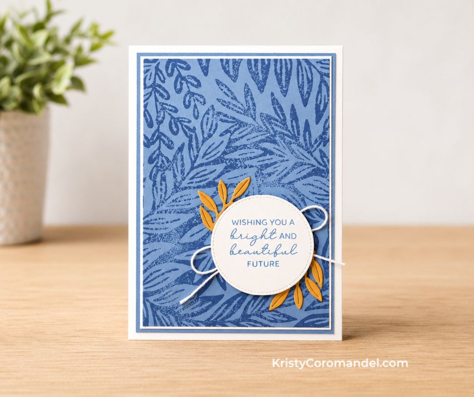 Handmade blue greeting card featuring the Moody Leaves Background Stamp in monochromatic blue tones with a layered white stitched circle sentiment, die-cut foliage accents and white twine on a white card base.