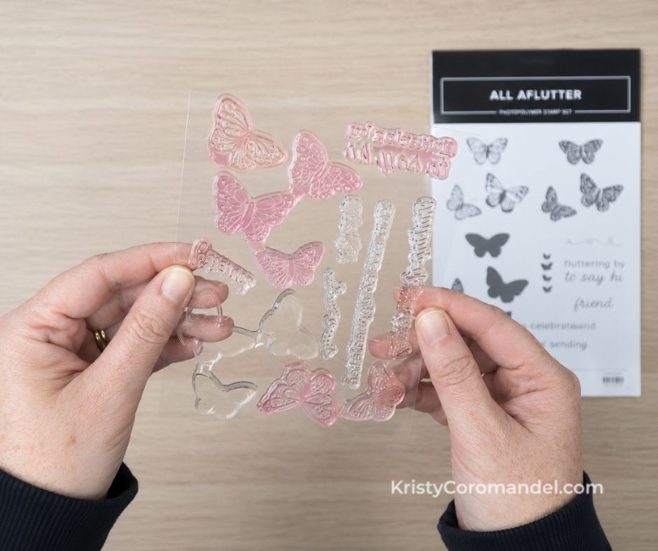 Hands holding a sheet of stained clear photopolymer stamps in front of the coordinating stamp set case, showing that colour staining is normal after repeated use.