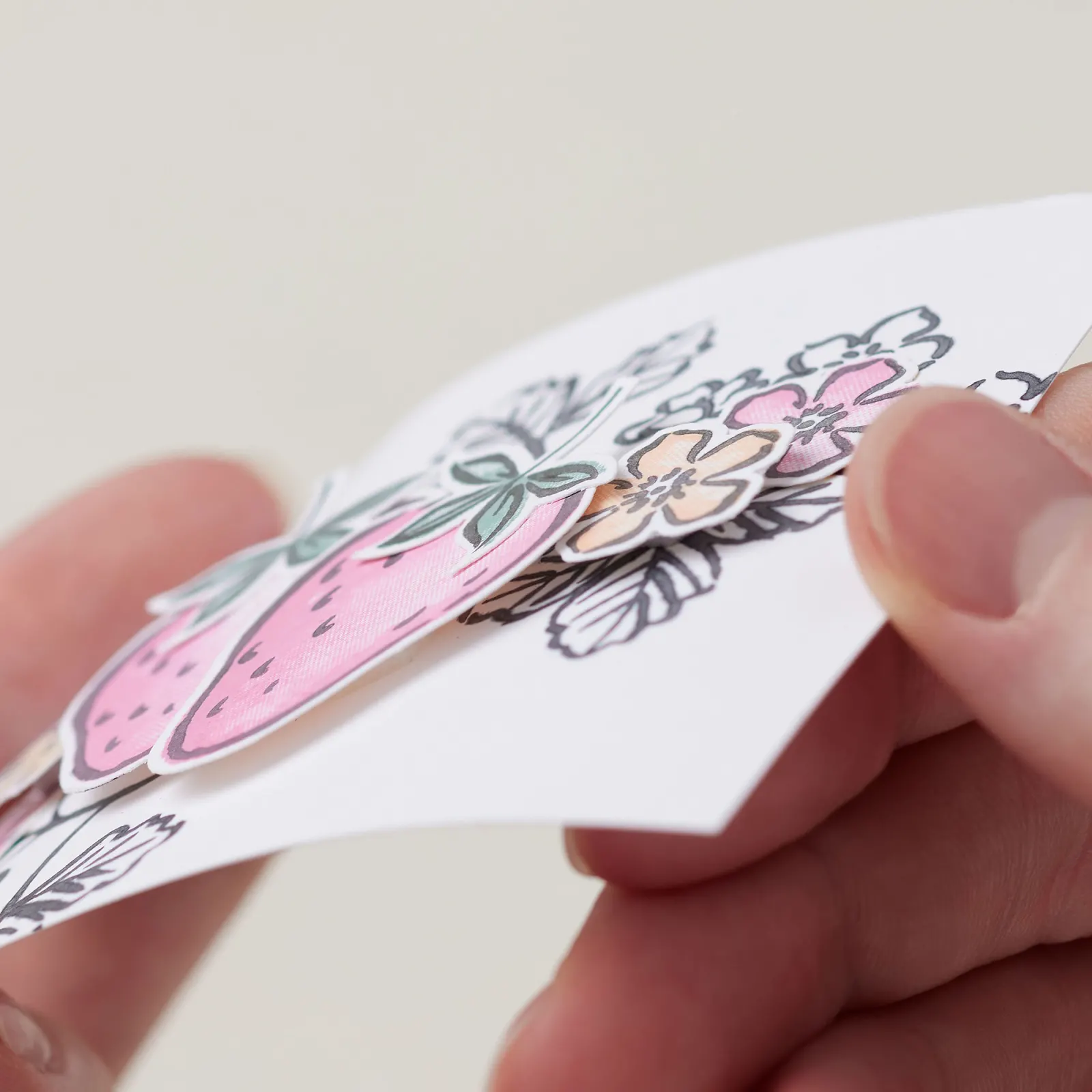 Close-up of layered flowers and strawberries raised with foam adhesive on a handmade card
